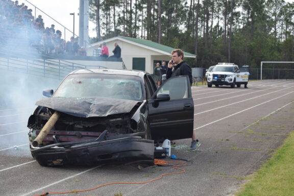 young man makes a phone call during a mock DUI accident