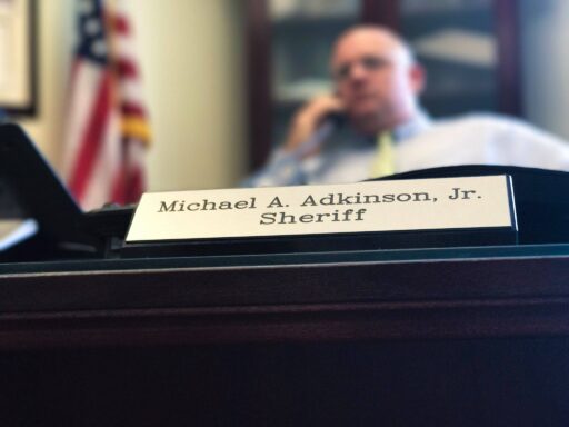 Sheriff Adkinson sitting behind desk with his nameplate in the foreground