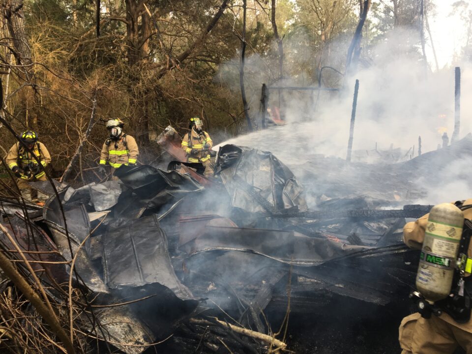 Firefighters spraying water on a burned home