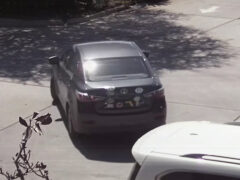 Back of Gray Toyota Yaris sedan with numerous bumper stickers on the trunk of the car