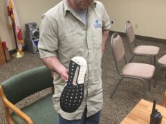 Suspect, Seth Snowden, holding his tennis shoes that he used to kick multiple vehicles over several days. 