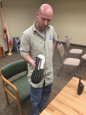 Suspect, Seth Snowden, holding his tennis shoes that he used to kick multiple vehicles over several days.