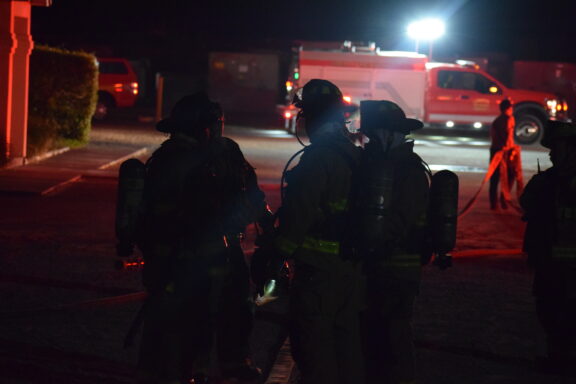 Firefighters Standing Outside in Front of Fire Truck at Night