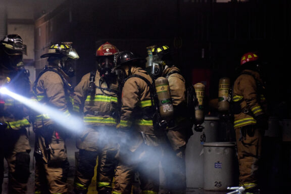 Firefighters Standing in Dark Building Shining a Flashlight
