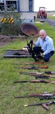 Captain Mark Collins holds up one of the 22 firearms recovered during a search warrant. 