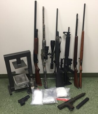 Guns, kilo press, and cocaine confiscated during a drug investigation.