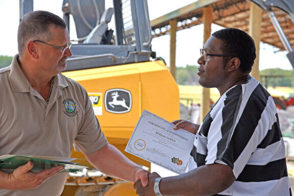 Inmate Receiving Certificate of Completion at Heavy Equipment Graduation Ceremony