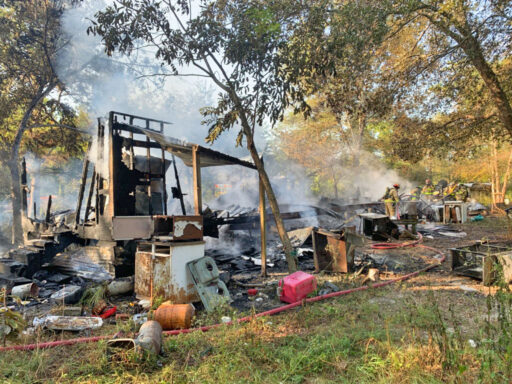 Firefighters spraying water on what's left of a mobile home after a structure fire