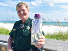 Sergeant Paula Pendleton holds a bottle that washed up on a Walton County beach.