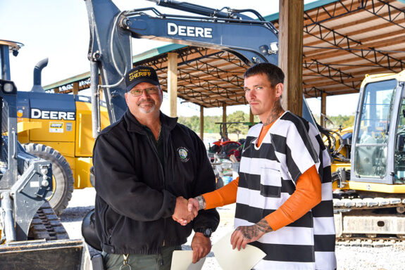 Inmate shaking instructor's hand at Heavy Equipment Graduation Ceremony