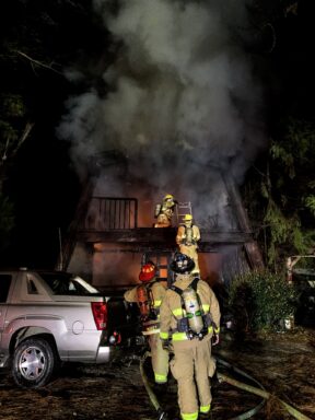 Firefighters in a line waiting to climb up to second story of home on fire