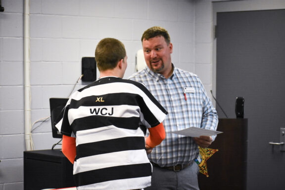 John Greehalgh, Northwest Florida State College welding instructor, shakes the hand of an inmate receiving his certificate.
