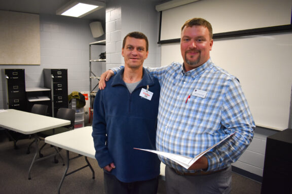 John Greehalgh, Northwest Florida State College welding instructor, smiles with an inmate receiving his certificate.