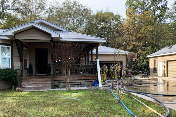 Firefighters Standing Outside of Garage of a Beige, Single-Story Home