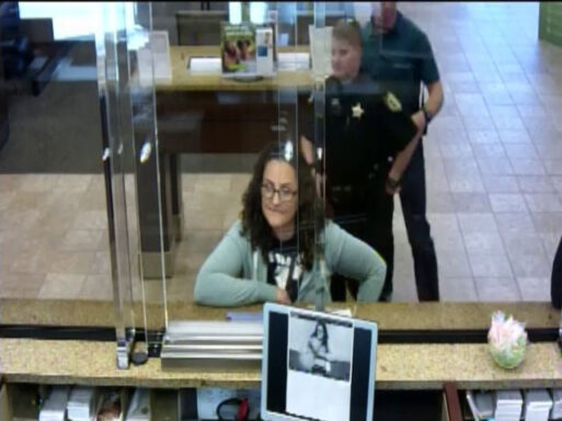 Woman standing in line at a bank with a deputy standing behind her.