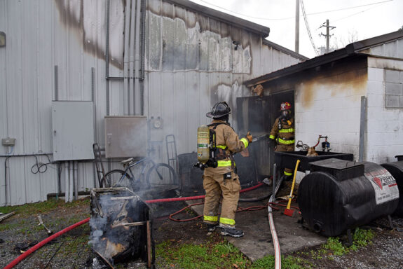 Firefighters standing outside of smoky building