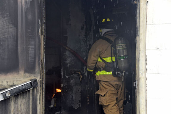 Firefighter inside dark, smoky room putting out fire