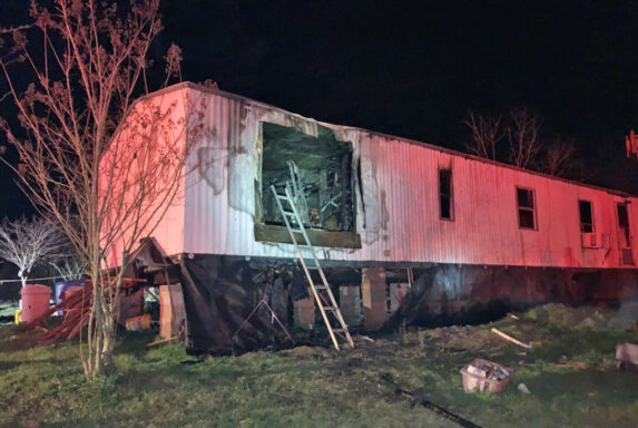 Ladder leaning up against single wide mobile home with smoke damage