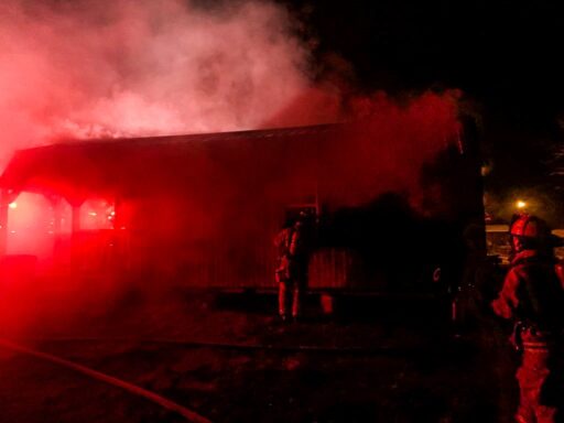 Firefighters working next to smoky building in the middle of the night