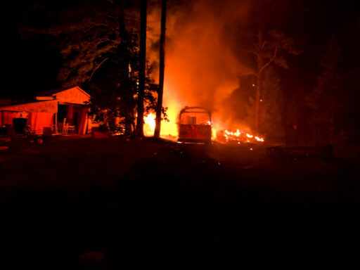 Flames coming from a motohome parked next to a large barn