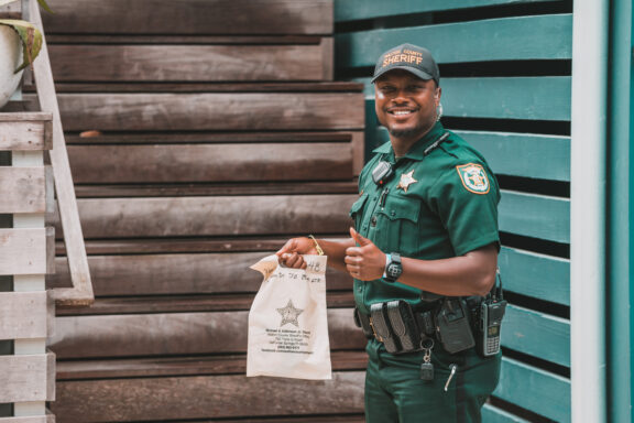 Deputy holding plastic bag holding a thumbs up. 