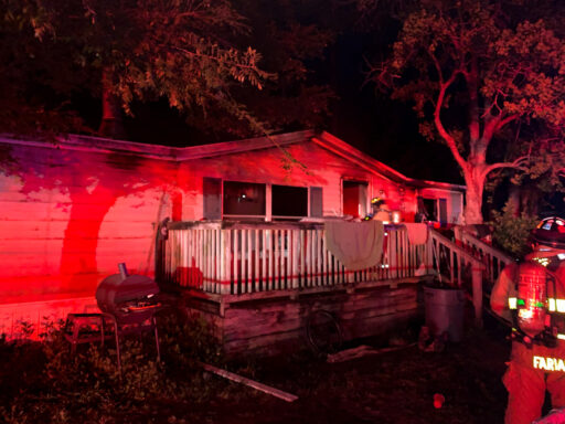 Firefighters entering a mobile home with smoke coming from the home