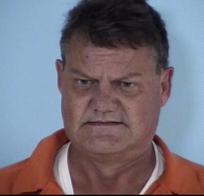 Mug shot of a white male with gray hair wearing an orange jumpsuit. 
