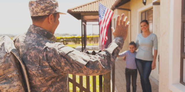 Military member waving at family on a porch. 
