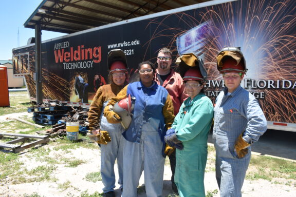 Four woman in welding gear pose with their instructor.