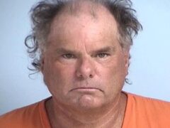 Mug shot of a white male in his 50's wearing an orange jumpsuit.