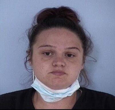 Mug shot of white female with brown hair and mask hanging below her chin