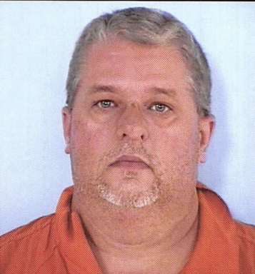 Mug shot of a white male with a gray and white goatee with an orange jumpsuit.