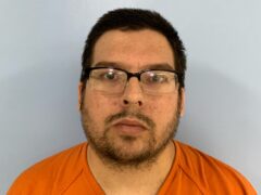 Mug shot of a white male with dark hair and black glasses