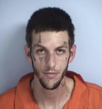 Mugshot of a hwite male with facial tattoos that look like a Jester wearing an orange jumpsuit.