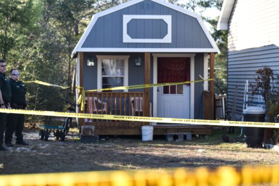 Crime Scene tape in front of a small shed. 