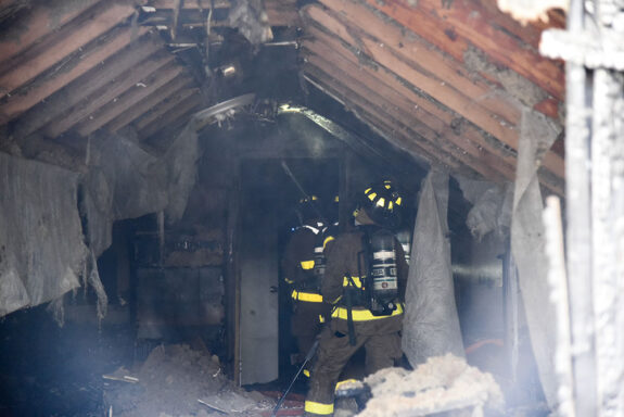 firefighters in damaged, smoke-filled room of a home