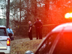 Deputies stand btween crime scene tape on a homicide call