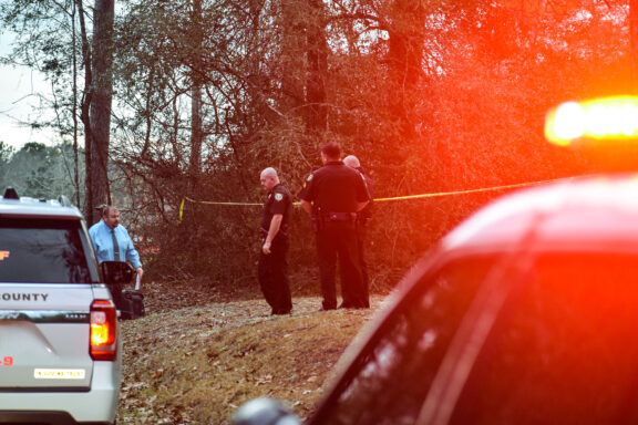 Deputies stand btween crime scene tape on a homicide call