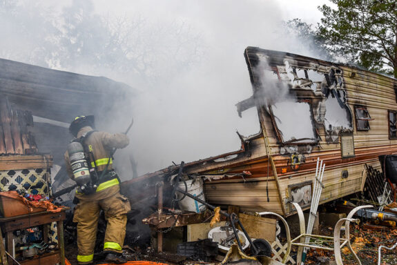 firefighter using tool inside smoke-filled camper