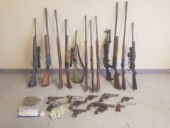 more than 20 guns lined up along with two large bags of marijuana and methamphetamine and cash