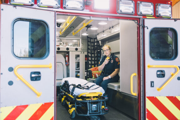 A paramedic uses a radio in the back of an ambulance