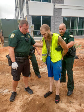 deputies patting down a light skinned black male with tattoos