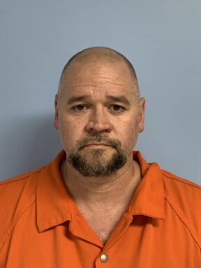 Mug shot of a white male with a bald head and brown goatee