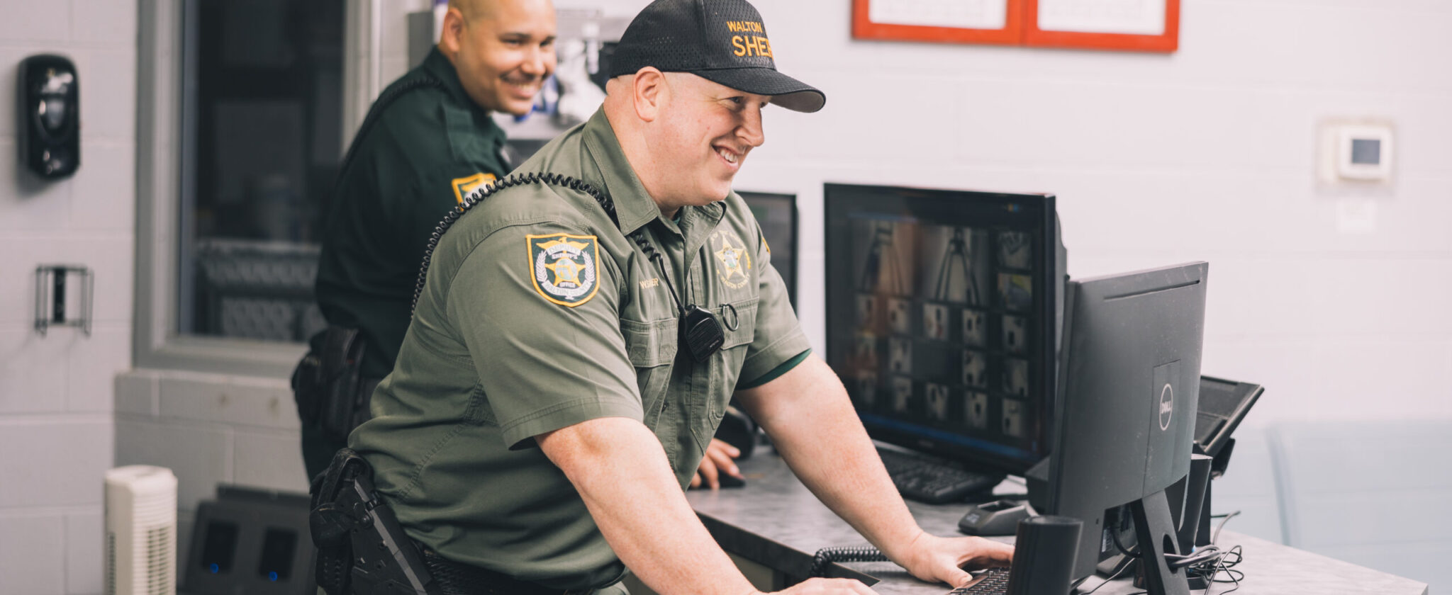 Two male detention deputies standing in front of computer
