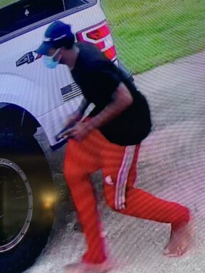 Black male wearing red pants carrying a handgun