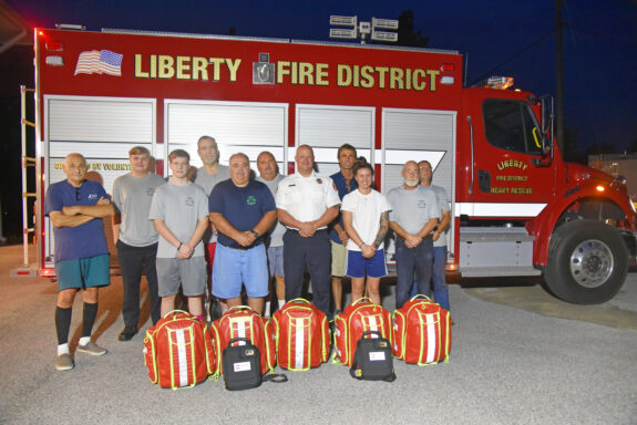 Volunteer Firefighters and Walton County Fire Rescue Chief standing in front of Liberty fire truck with medical supplies