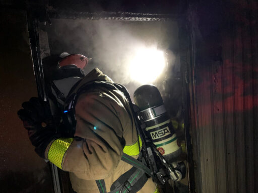 Firefighter standing in doorway of home with bright light shining through