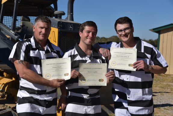three inmates holding certificates