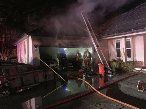 firefighters inside garage inspecting roof of burning garage