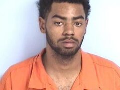 Mug shot of a black male with facial hair in an orange jumpsuit